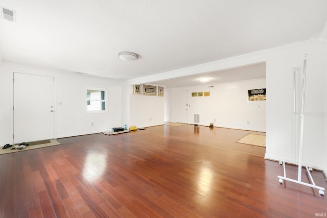 unfurnished living room with visible vents, crown molding, and wood finished floors