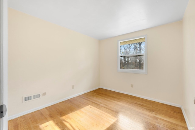 spare room with light wood-style floors, baseboards, and visible vents