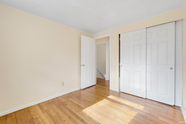 unfurnished bedroom with baseboards, a closet, and light wood-style floors