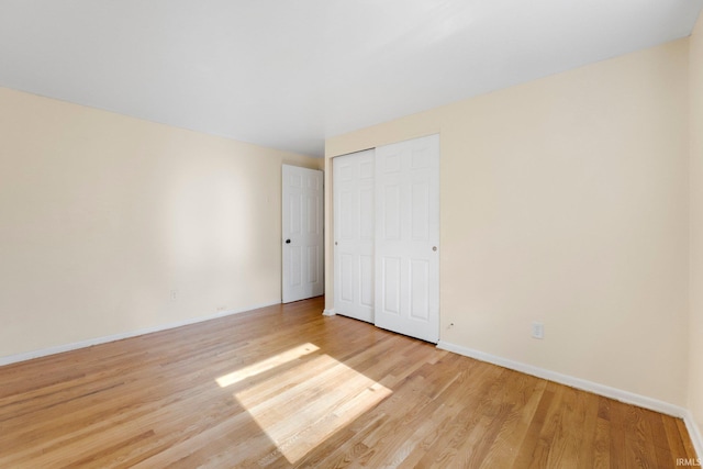 unfurnished bedroom with a closet, light wood-style flooring, and baseboards