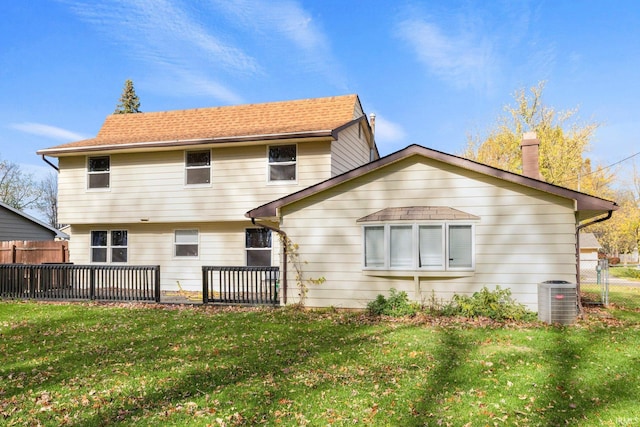 rear view of property with fence, a lawn, a chimney, and central AC unit