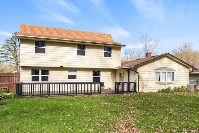 back of house with a shingled roof, central air condition unit, a yard, and fence