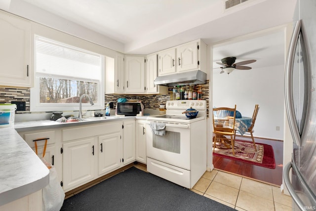 kitchen featuring electric range, stainless steel fridge, white cabinetry, and under cabinet range hood