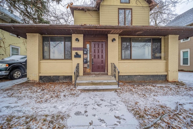 snow covered property entrance featuring brick siding