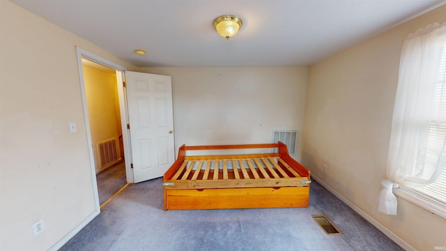 unfurnished bedroom featuring baseboards, visible vents, and dark carpet