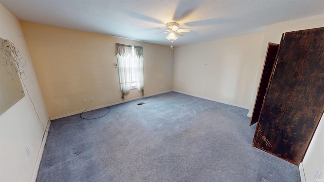 empty room with carpet, visible vents, ceiling fan, a textured ceiling, and baseboards