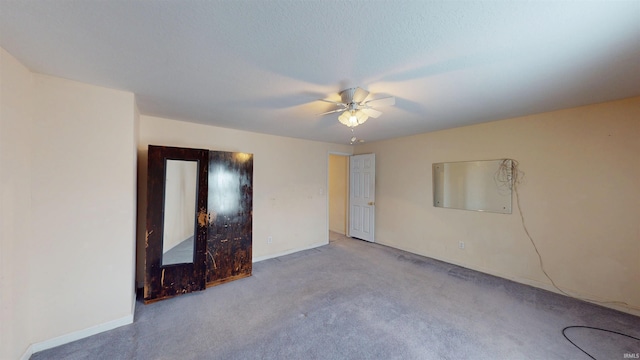 spare room featuring light colored carpet, ceiling fan, and baseboards