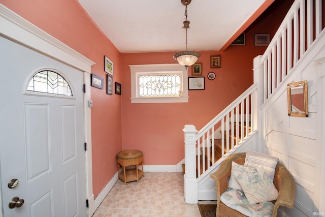 foyer entrance with light tile patterned floors, stairway, and baseboards