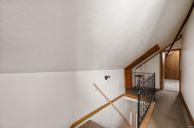 interior space with a textured ceiling, carpet flooring, lofted ceiling, and baseboards