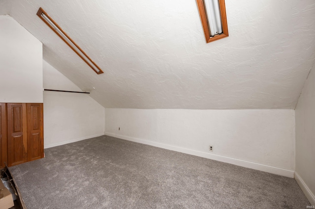 additional living space featuring carpet, baseboards, vaulted ceiling, and a textured ceiling