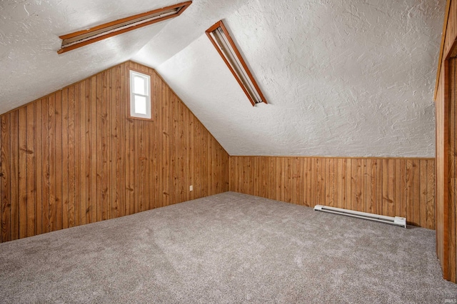 bonus room with carpet floors, lofted ceiling, wood walls, and a textured ceiling