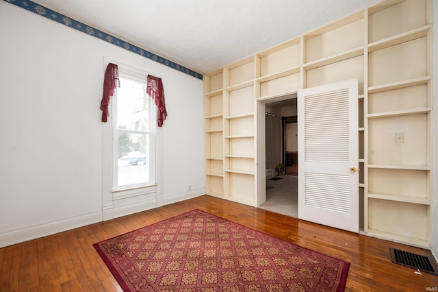 interior space with dark wood-type flooring, visible vents, a textured ceiling, and baseboards