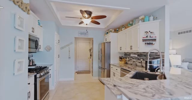 kitchen with visible vents, a raised ceiling, appliances with stainless steel finishes, light stone counters, and white cabinetry