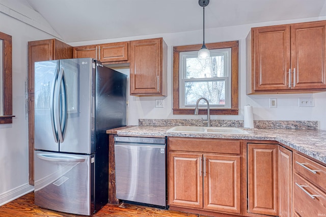 kitchen featuring appliances with stainless steel finishes, brown cabinets, hanging light fixtures, light countertops, and a sink