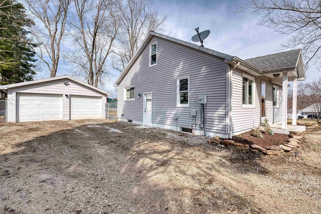 view of side of property with a shingled roof, a detached garage, and an outdoor structure