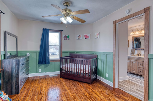 bedroom featuring a textured ceiling, a sink, visible vents, wainscoting, and dark wood-style floors