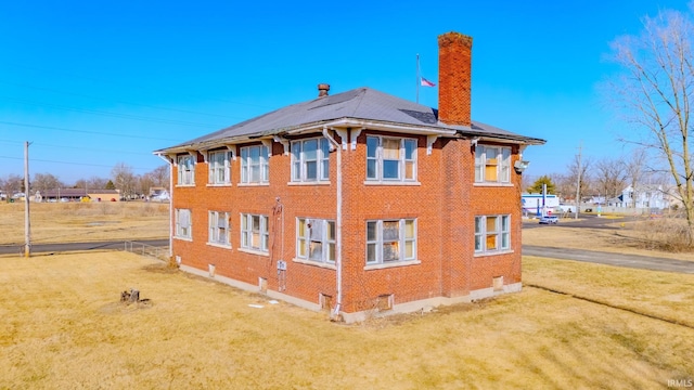 view of home's exterior with brick siding, a yard, and a chimney