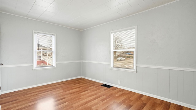 unfurnished room with wainscoting, visible vents, and wood finished floors