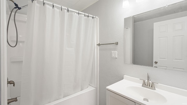 full bathroom with shower / tub combo, a textured wall, and vanity