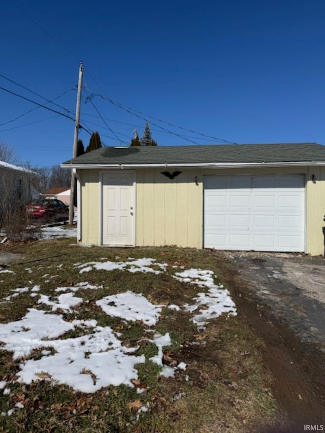 snow covered garage featuring aphalt driveway