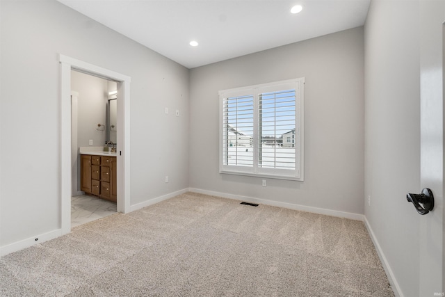 unfurnished bedroom with visible vents, baseboards, light colored carpet, ensuite bath, and recessed lighting