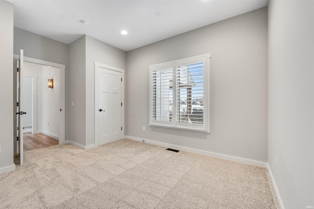 unfurnished room with light carpet, recessed lighting, visible vents, and baseboards