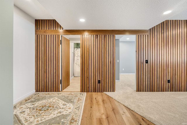 spare room with recessed lighting, wooden walls, a textured ceiling, and wood finished floors