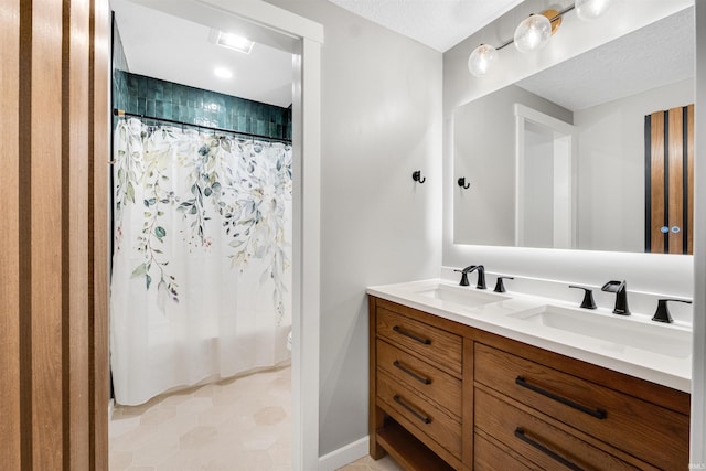 bathroom featuring a sink, a textured ceiling, and double vanity