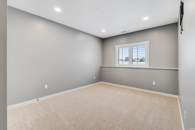 carpeted spare room with recessed lighting, visible vents, a textured ceiling, and baseboards