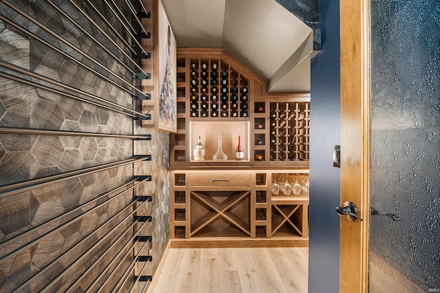 wine room with light wood-style floors and lofted ceiling