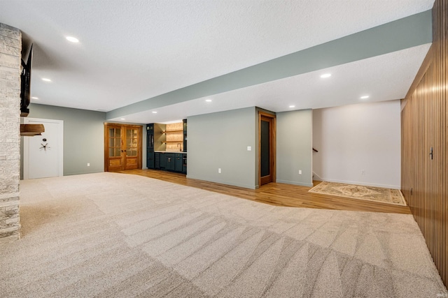 unfurnished living room with carpet, recessed lighting, a textured ceiling, wood finished floors, and baseboards