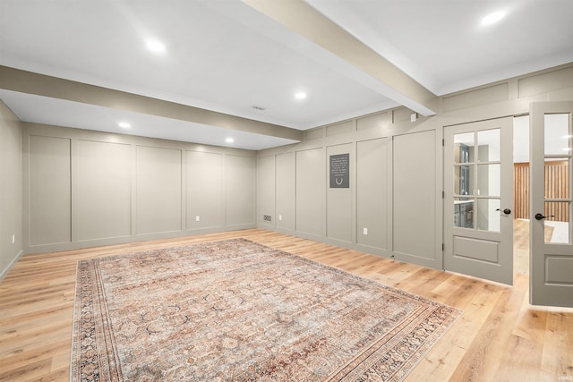 below grade area with light wood-style floors, recessed lighting, visible vents, and a decorative wall