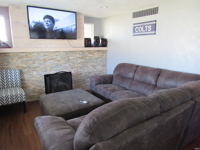 living area with a stone fireplace, wood finished floors, and visible vents