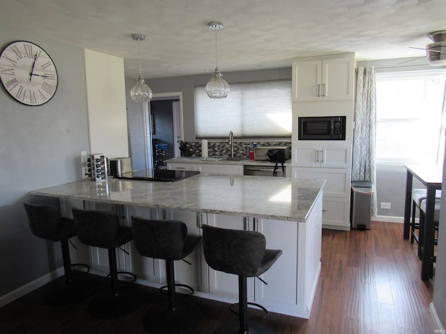 kitchen featuring hanging light fixtures, white cabinetry, a sink, a peninsula, and black appliances