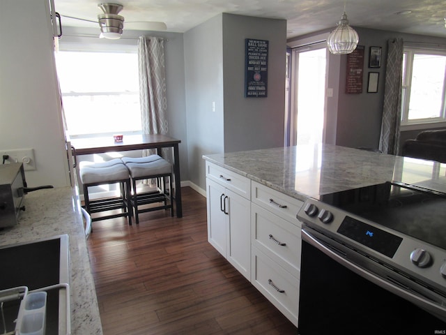 kitchen featuring hanging light fixtures, light stone countertops, white cabinetry, and stainless steel electric stove