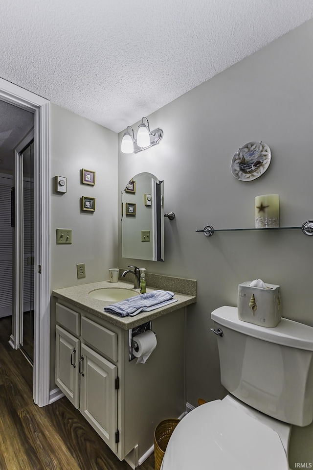 bathroom featuring a textured ceiling, toilet, wood finished floors, and vanity