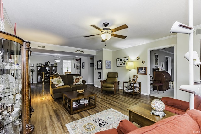 living room with ornamental molding, ceiling fan, dark wood-type flooring, and visible vents