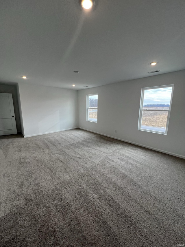 spare room with carpet, visible vents, and baseboards