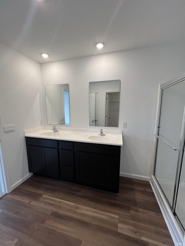 full bath with baseboards, a sink, and wood finished floors