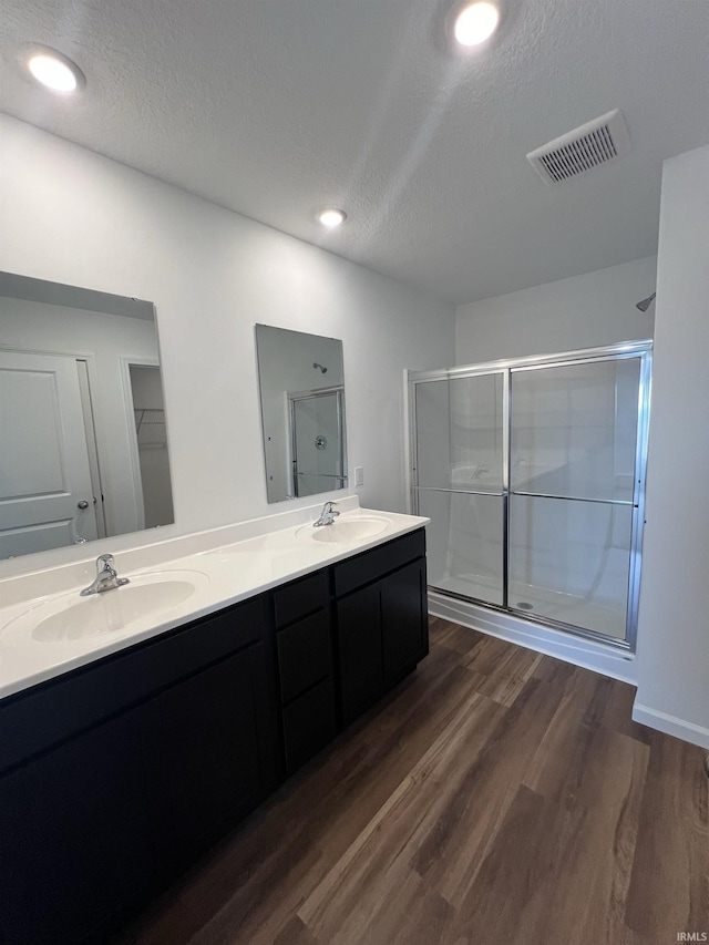 bathroom featuring visible vents, a sink, a textured ceiling, and wood finished floors