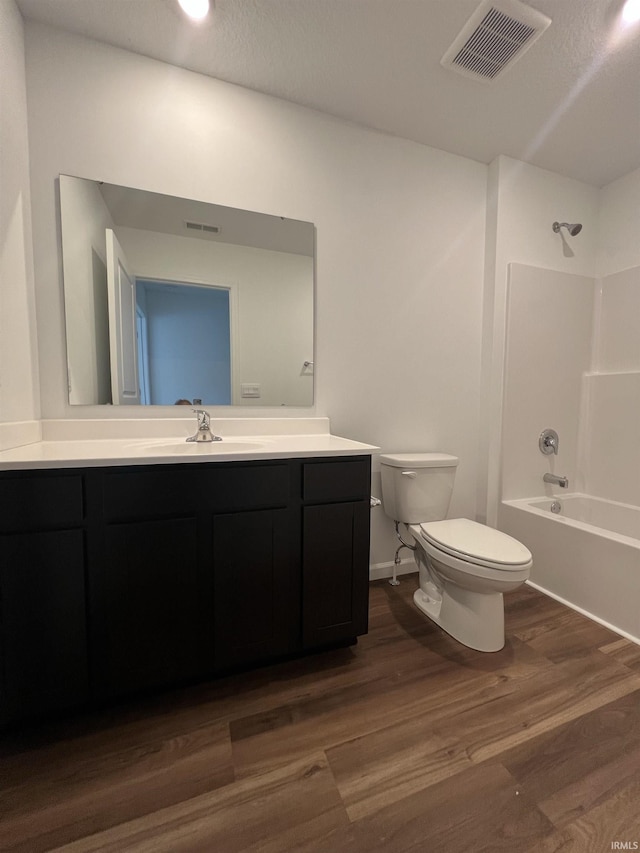 bathroom with shower / bath combination, visible vents, toilet, vanity, and wood finished floors