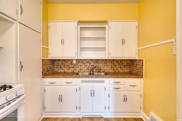 kitchen with white cabinetry, a sink, and open shelves