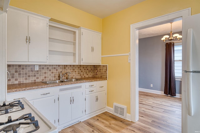 kitchen featuring pendant lighting, open shelves, visible vents, freestanding refrigerator, and white cabinetry