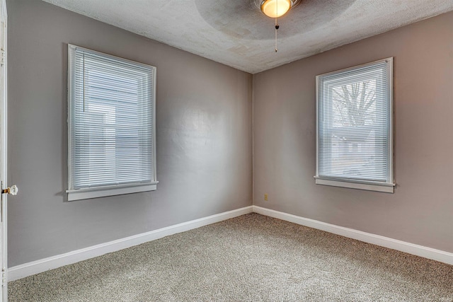 carpeted spare room featuring ceiling fan, baseboards, and a textured ceiling