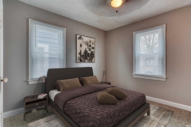 carpeted bedroom with a ceiling fan, a textured ceiling, and baseboards