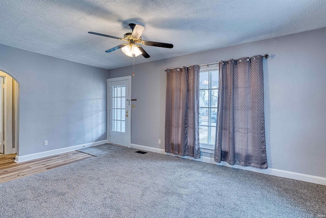 unfurnished room featuring arched walkways, baseboards, visible vents, and carpet