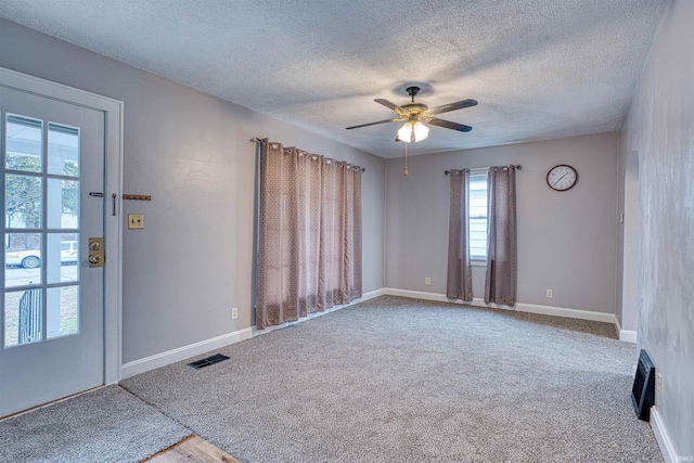 carpeted spare room with ceiling fan, a textured ceiling, visible vents, and baseboards