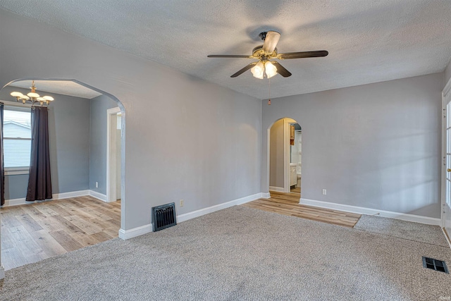 spare room with arched walkways, light carpet, and visible vents