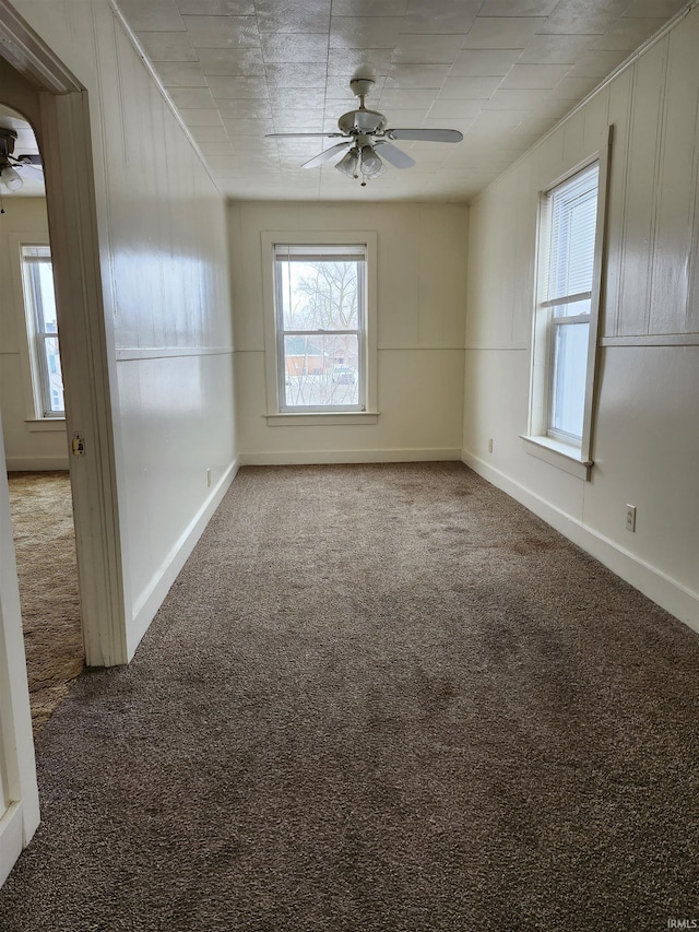 empty room featuring carpet floors, a ceiling fan, and baseboards