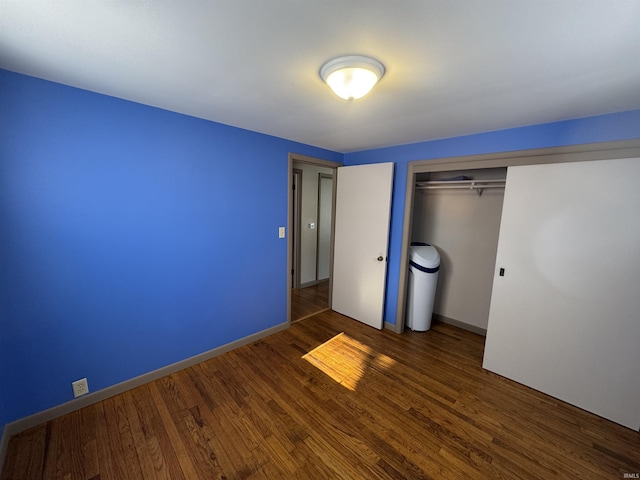 unfurnished bedroom with dark wood-style floors, baseboards, and a closet